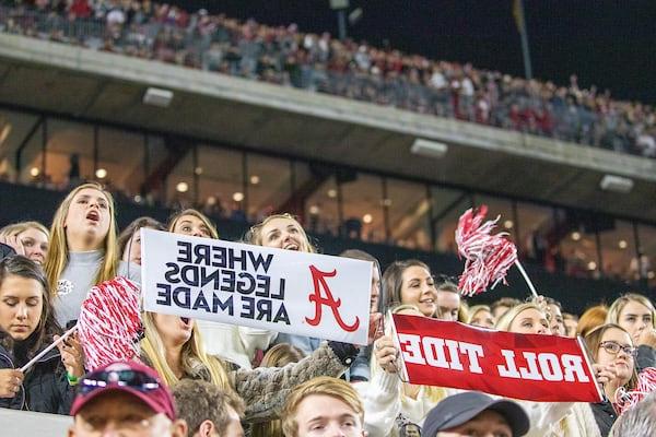 Fans in Bryant-Denny stadium hold up Where Legends Are Made banners